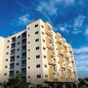 阿克拉Accra Luxury apartments at Oasis Park Residences的一座高大的公寓楼,后面有蓝色的天空