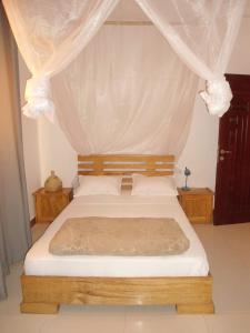 达喀尔Daaru Jamm的一间卧室配有一张带天蓬的床