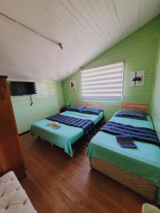 奥索尔诺Hostal Paradise Blue的一间设有三张床和一台电视的房间