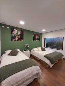 巴尼奥斯593 Hotel Boutique Baños的卧室设有两张床铺和绿色的墙壁