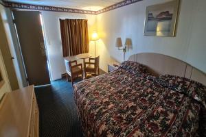 杜波依斯DuBois Manor Motel by OYO的酒店客房配有一张床铺和一张桌子。