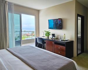 曼塔海菊蛤珍珠酒店的一间卧室配有一张床、一张书桌和一台电视