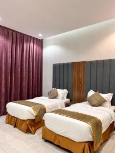 吉赞سرايا ان شاليهات وغرف فندقية的紫色窗帘间内的两张床