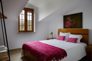 阿加尼尔Casas do Oiteirinho的一间卧室配有一张带粉色毯子的大床