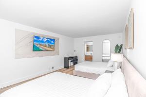 默特尔比奇Fifth and Ocean的一间白色卧室,配有两张床和电视