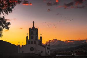 瓦拉斯Amplias y Centricas Habitaciones Huaraz WIFI, AGUA CALIENTE的日落时顶有十字架的教堂