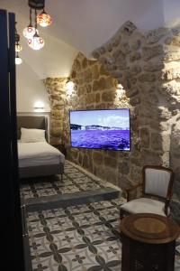 阿卡Shafika house的一间卧室设有一张床,石墙上配有电视。