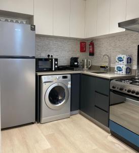 沙迦1 BR Luxury Apt by AJ Aljada的厨房配有洗衣机和水槽