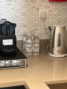 沙迦1 BR Luxury Apt by AJ Aljada的厨房柜台配有咖啡壶和瓶装水。