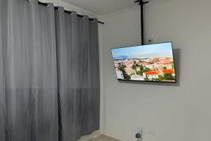 圣维森特岛Apartamento *Vista da Ilha* - Novo Lançamento!的挂在窗帘旁墙上的平面电视