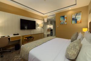 奥兰2H Hotel的酒店客房配有一张床、一张书桌和一台电视。