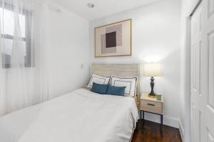 纽约69-5B I Stylish Lower East Side 1BR Apt BRAND NEW的白色卧室配有蓝色枕头的床