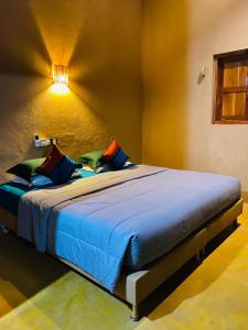 蒂瑟默哈拉默麦维里吉酒店的一间卧室配有一张带蓝色床单和彩色枕头的床。