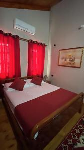 克鲁亚ROOMS EMILIANO Castle of Kruja的一间卧室配有一张带红色窗帘的大床