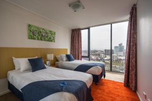 墨尔本IMSA集团公寓的酒店客房设有两张床和大窗户。