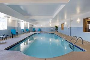 查尔斯顿Comfort Inn & Suites Airport Convention Center的大楼内带蓝色椅子的大型游泳池