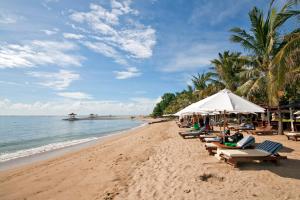 登巴萨Jenna Residence Denpasar的海滩上设有椅子和遮阳伞,还有大海