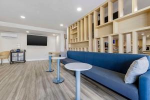 圣地亚哥Comfort Inn Sea World Area的客厅配有蓝色的沙发和2张桌子