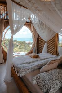 珀尼达岛Camanta Penida - Adult Only的一间卧室设有一张带大窗户的天蓬床