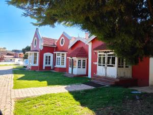 乌提Heritage Inn by Brown Tree Resorts的一间红色的房子,有白色的门和院子