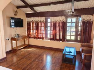 乌提Heritage Inn by Brown Tree Resorts的客厅铺有木地板,设有窗户和桌子。