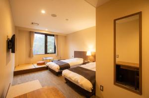 富士河口湖Motosu Phoenix Hotel的酒店客房,设有两张床和镜子