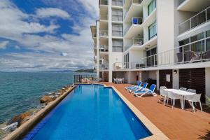 耐莉湾Best at Bright Point Absolute Waterfront Apartment的一座游泳池位于一座毗邻大海的建筑前