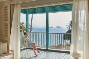 阁遥岛Cape Kudu Hotel, Koh Yao Noi的坐在俯瞰大海的阳台的吊床上的女人