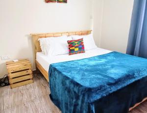 金贾Amaryllis blue,8mins source to River Nile,secure, peaceful, central great location的一间卧室配有一张带蓝色毯子的床
