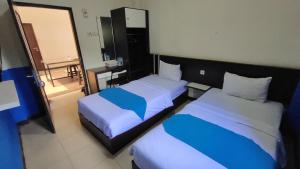 RantauOYO 93775 Nilam Guest House的酒店客房,设有两张床和镜子