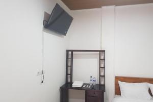 棉兰OYO 93709 Rose Inn 2的一间带镜子、一张床和电视的卧室