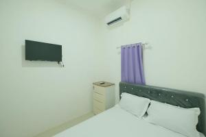 Laleng-balandaeOYO 93756 Qq Kost的卧室配有一张床,墙上配有电视。