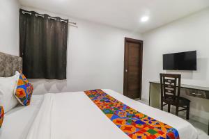 新德里FabExpress Super 8 Residency的一间卧室配有一张床、一张书桌和一台电视