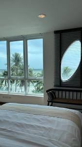 邦盛The Beach Bangsaen by Thanthita next to Wonnapa beach的一间卧室设有床铺和种有棕榈树的窗户。