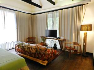 清迈Baan Saen Fang Chiang Mai - SHA Plus的一间卧室配有一张床、一台电视和一张沙发