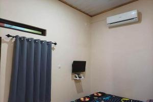 井里汶OYO 93741 Ayna Kost Syariah的一间设有蓝色窗帘、一张床和加热器的房间