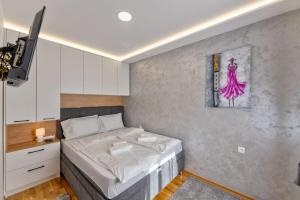 兹拉蒂博尔Apartman Hanah Vip Bogic的卧室配有一张床,墙上挂有绘画作品