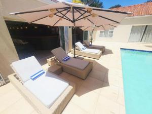 BedfordviewVilla Reis - The Villa of Kings的游泳池旁的2把躺椅和遮阳伞