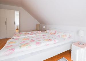 NiedermennigHaus Elfriede的白色卧室,配有白色的粉红色花卉床