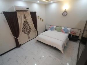 伊斯兰堡Edge of Islamabad Entrance的卧室配有一张床,墙上挂着一个钟
