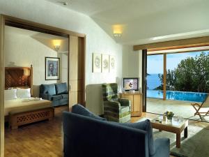 伊罗达Porto Elounda Golf & Spa Resort, Six Senses Spa的一间带一张床的客厅和一间享有美景的房间