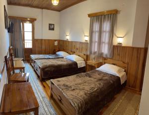 美特索文HOTEL MARI Metsovo的酒店客房设有两张床和一张桌子。