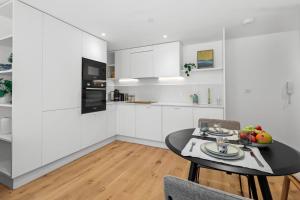 伊斯特布恩Chic Urban Retreat: Modern Apartment in Eastbourne的厨房配有白色橱柜和桌椅