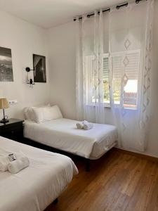 珀彻斯Castelo da Esperança na Vila Sra da Rocha的配有白色窗帘和窗户的客房内的两张床