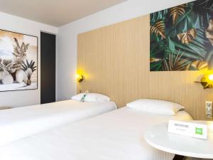 特鲁瓦ibis Styles Troyes Centre的客房设有两张床、一张桌子和一幅画