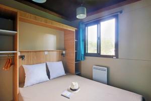 艾克塞恩维克斯Camping La Pinède的一间卧室配有一张带窗户和帽子的床