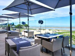 沙特拉永普拉日La Grande Terrasse Hotel&Spa La Rochelle MGallery Hotel Collection的一间设有桌椅的餐厅,享有海滩美景