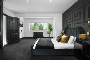 ShenstoneGorgeous 6 Bed House - Hot Tub - Wifi & Large Garden - Lichfield 40ST的一间卧室配有一张大床和黑色床头板