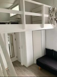 斯坎讷堡Small cosy appartment的一张白色的阁楼床,在房间内配有黑色沙发