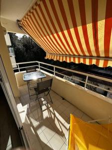 阿卡雄Appartement centre Arcachon的阳台配有桌子和条纹雨伞
